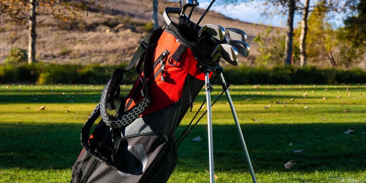 A red golf bag on a golf course, filled with clubs | Source: Pexels