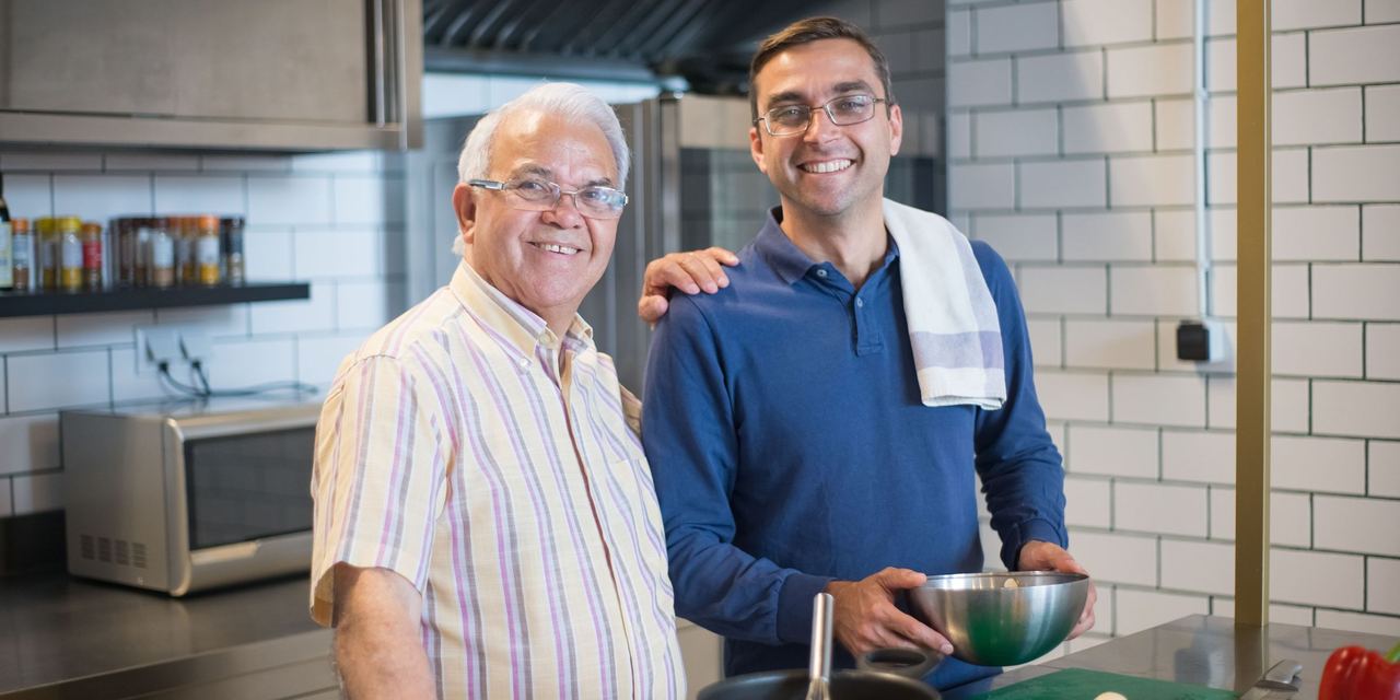 A happy older man posing with a younger one in a kitchen | Source: Pexels