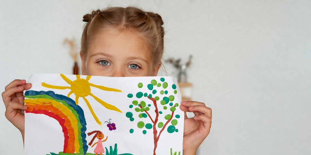 A little girl holding up a colorful drawing | Source: Magnific