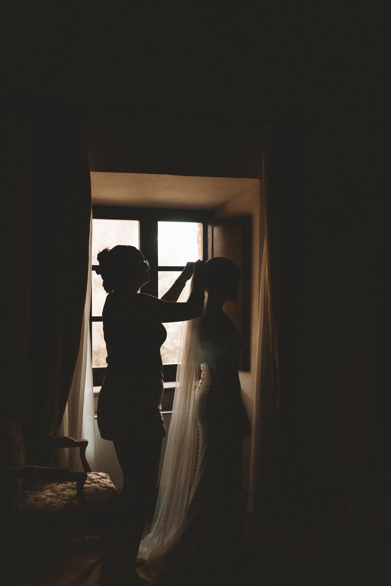 Silhouette of wedding veil adjustment by window | Source: Pexels