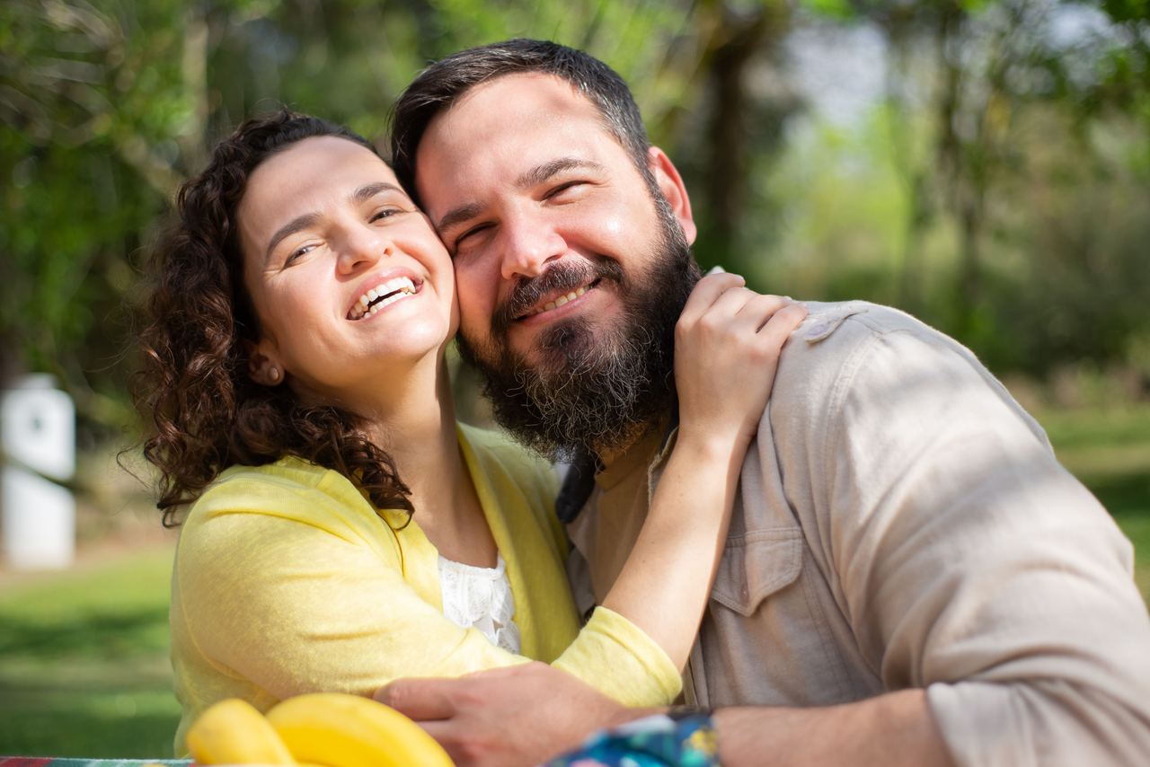 A happy couple smiles and embraces in a sunlit park | Source: Pexels