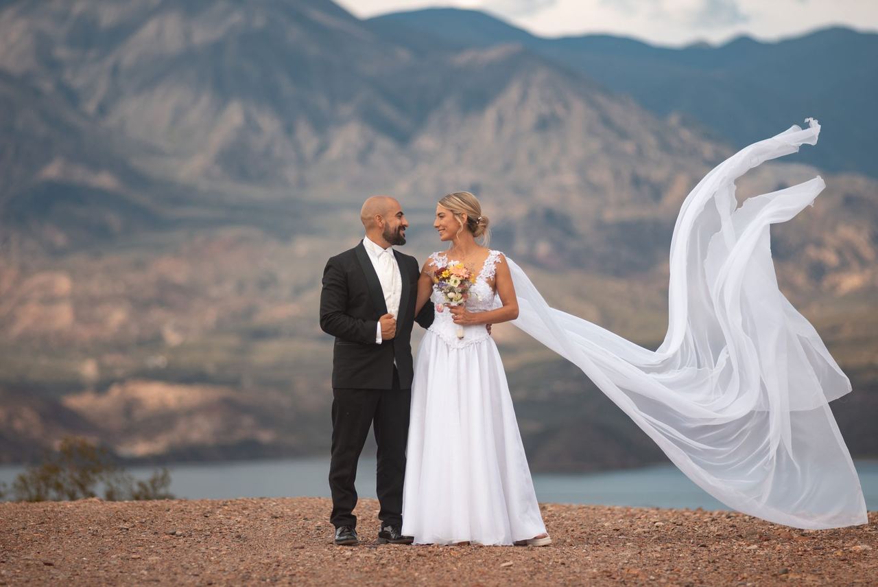 An elegant bride and groom in wedding attire against the backdrop of picturesque mountains | Source: Pexels