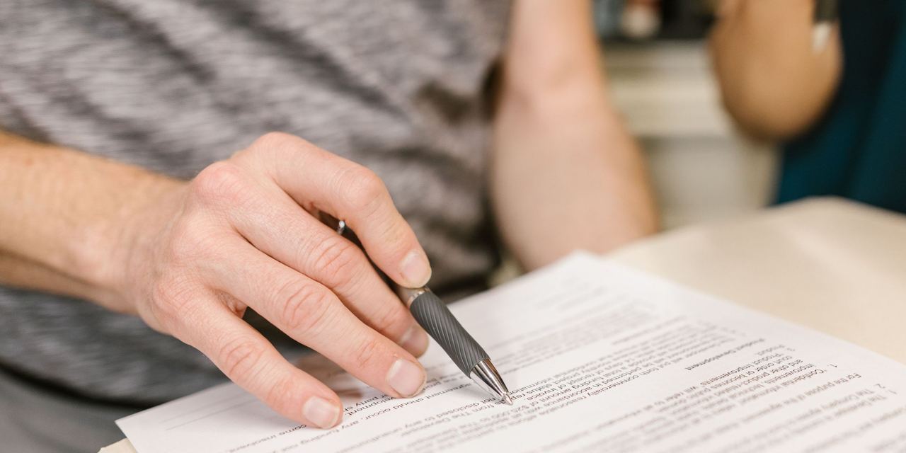 A close-up of a person's hand holding a pain over a legal document | Source: Pexels