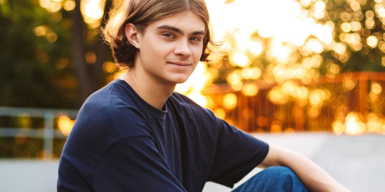 A teenage boy sitting outdoors at sunset | Source: Freepik