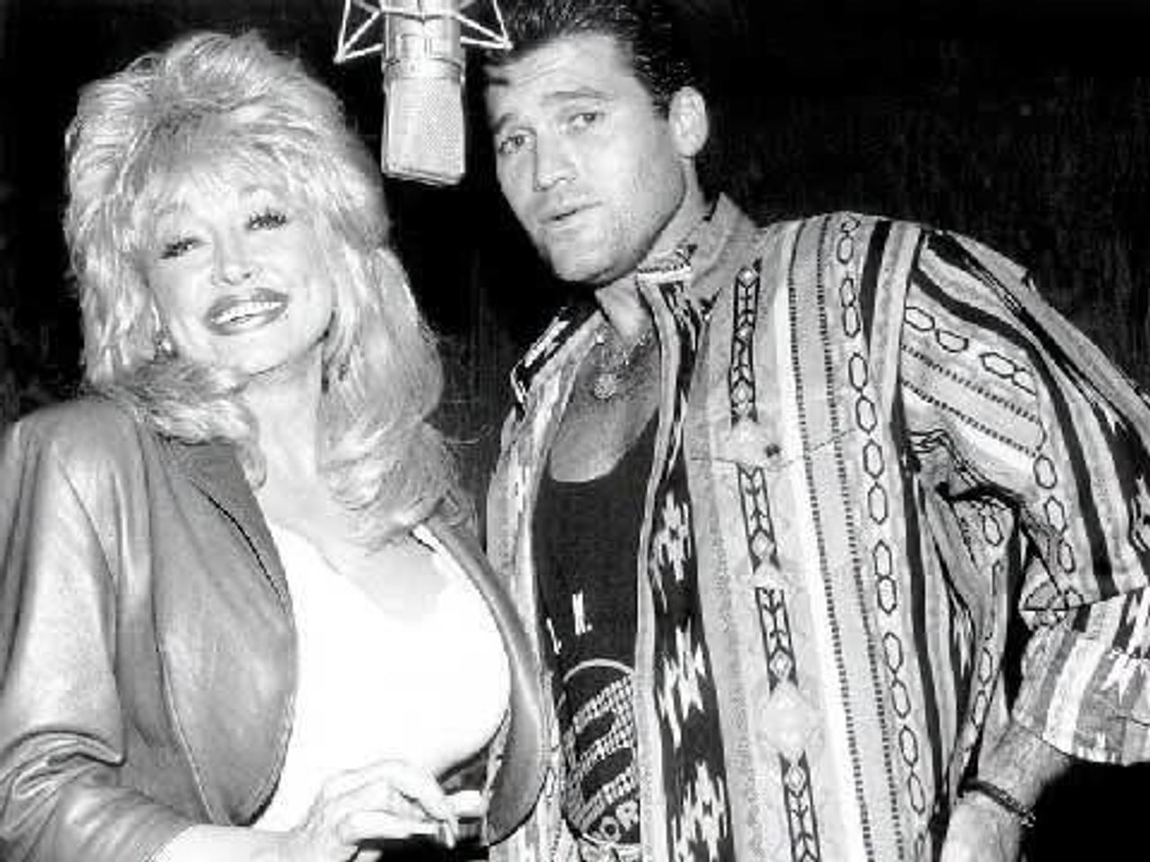 In the studio: Dolly Parton smiles as she shares a microphone with Billy Ray Cyrus during a recording session in this vintage black and white photograph. | Source: Facebook/BillyRayCyrus