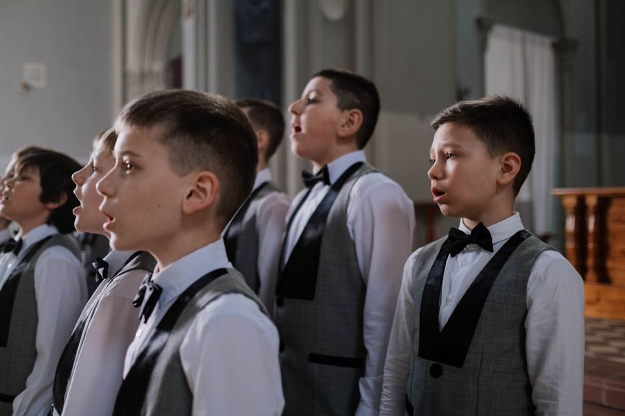 Boys dressed in uniform singing in a church choir during a performance.