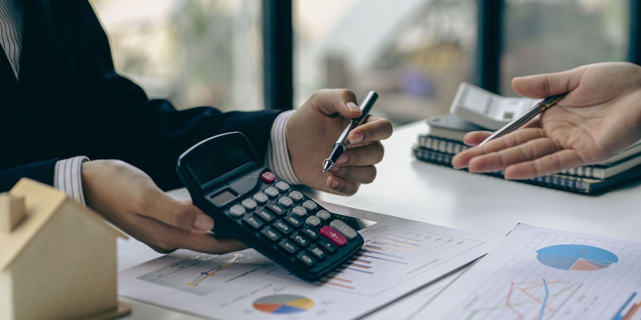 Two people doing calculations and paperwork | Source: Shutterstock