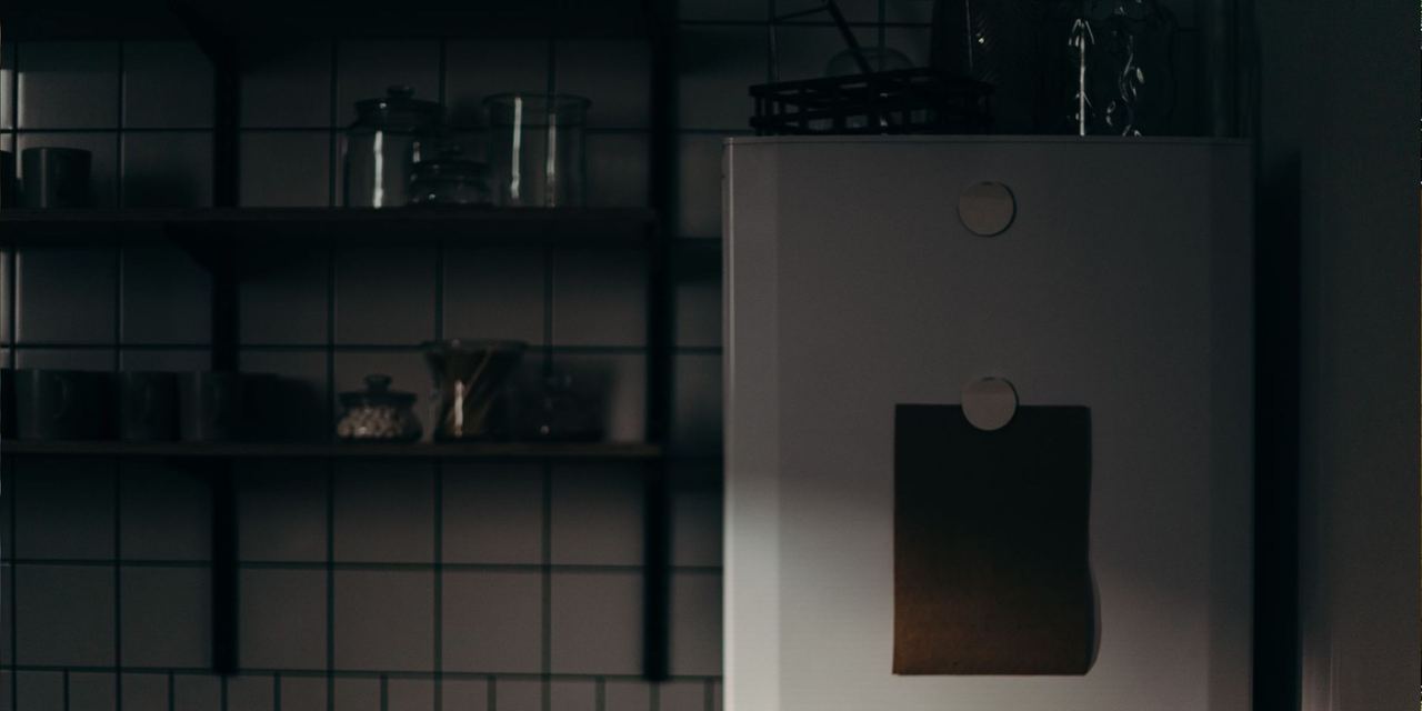 A dark and gloomy kitchen interior with a refrigerator and shelves | Source: Pexels