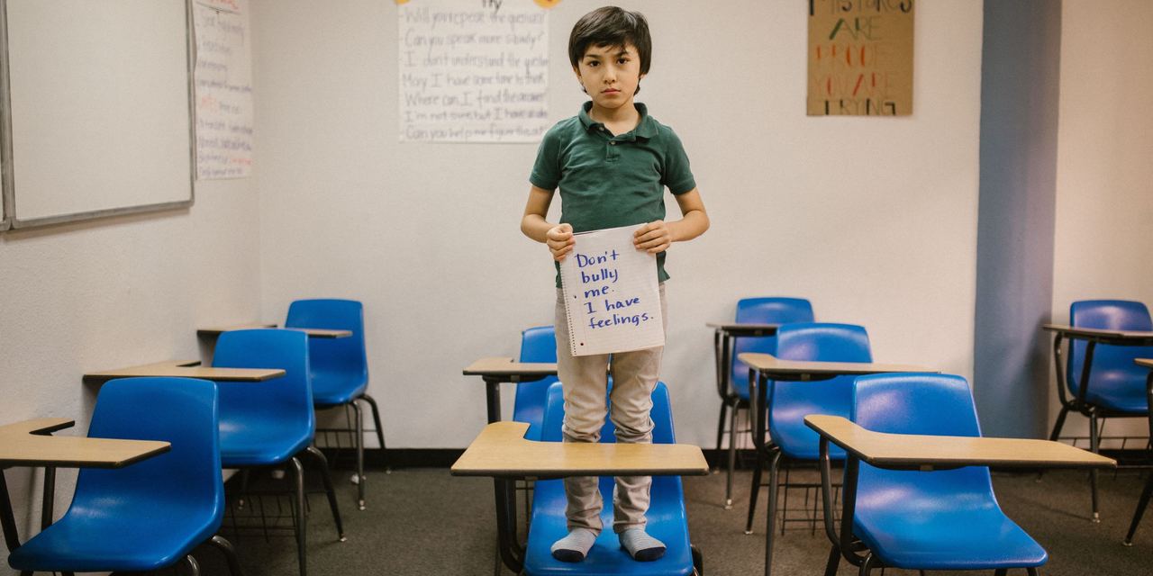 A little boy standing in a classroom and holding a sign | Source: Pexels