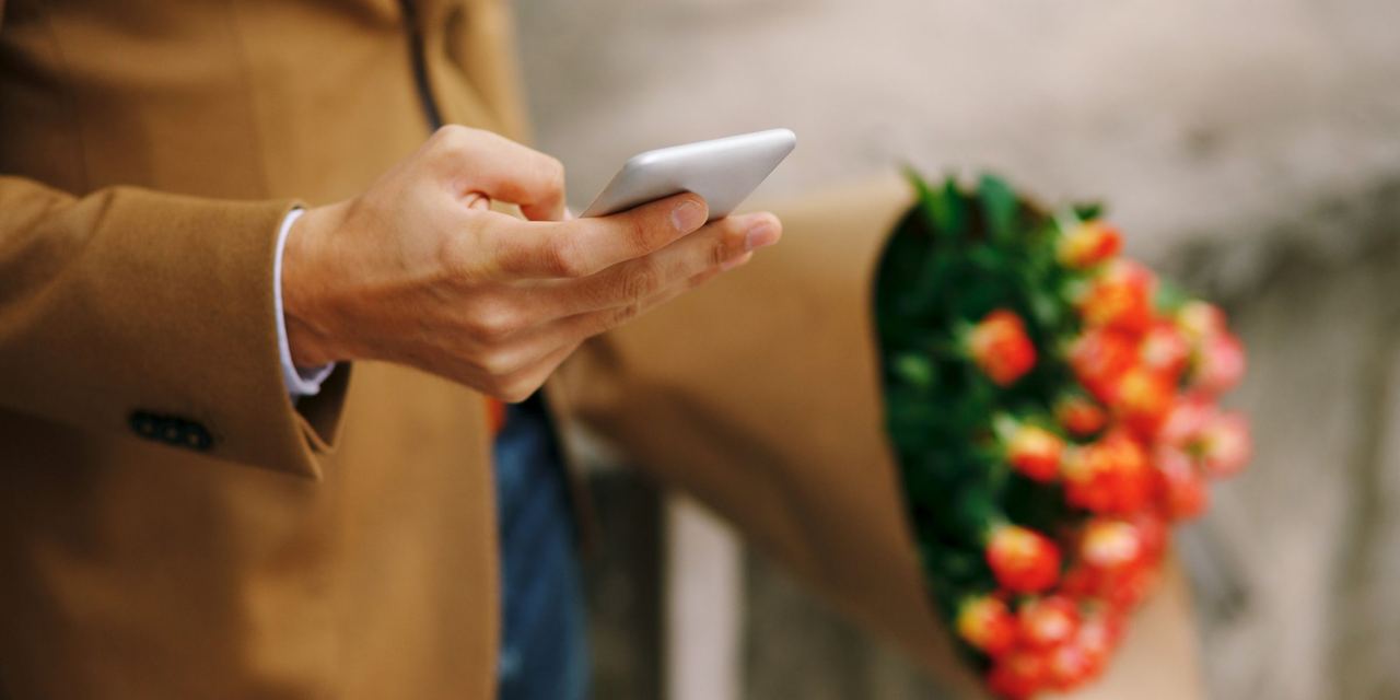 A man holding a phone and flowers | Source: Magnific