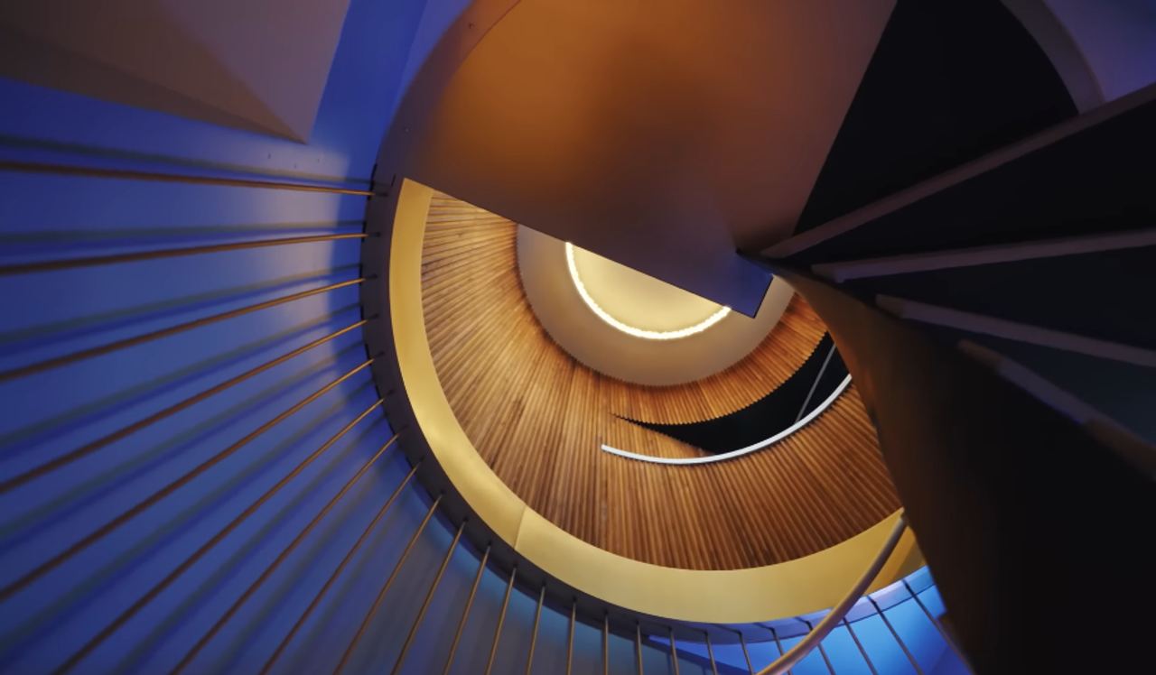 The custom staircase is one of the home's most dramatic architectural moments — and one of Christopher's personal favorites. Its twisting metal structure turns a practical connection between two floors into a piece of sculpture. | Source: YouTube/Architectural Digest