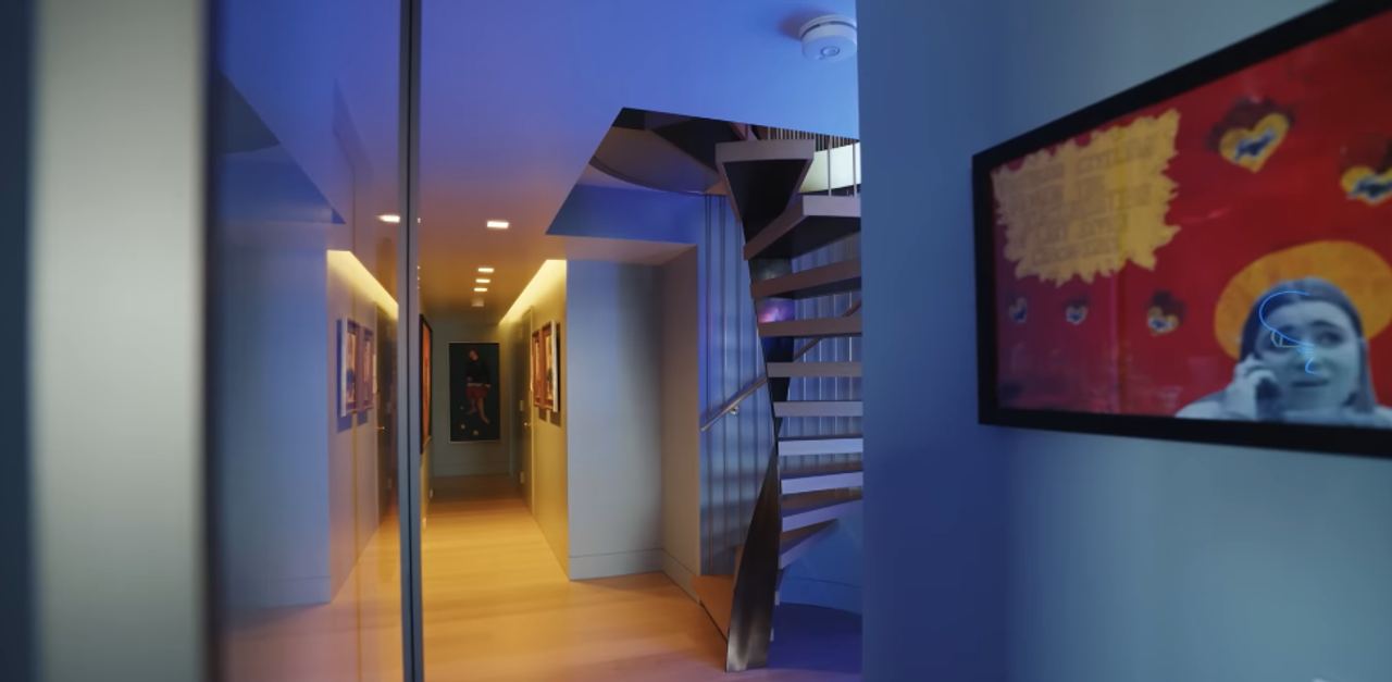 Seen from below, the staircase looks almost like an art installation tucked into the family's gallery-like lower level. It became the elegant answer to a very basic problem: the two floors originally were not connected at all. | Source: YouTube/Architectural Digest