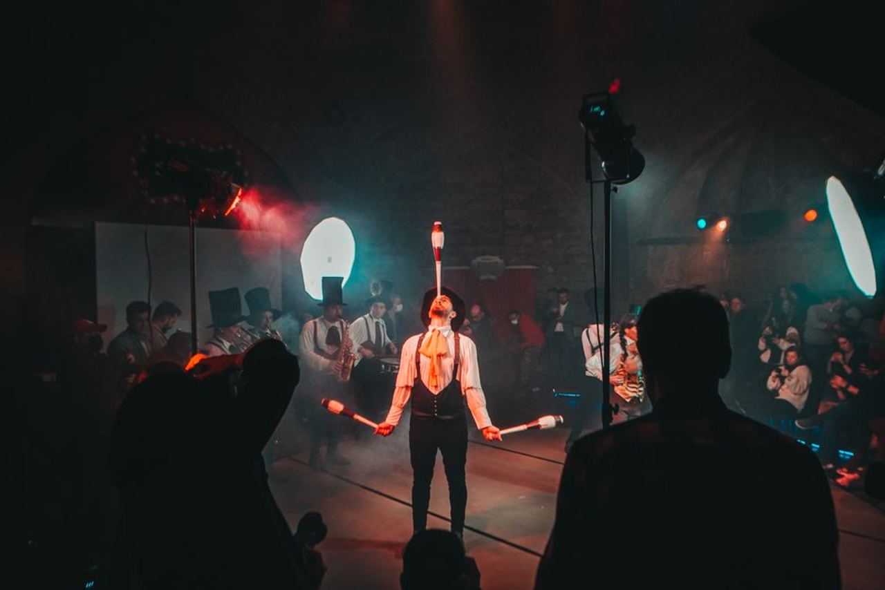 A mesmerizing circus juggler performs under dramatic lighting during a lively festival.