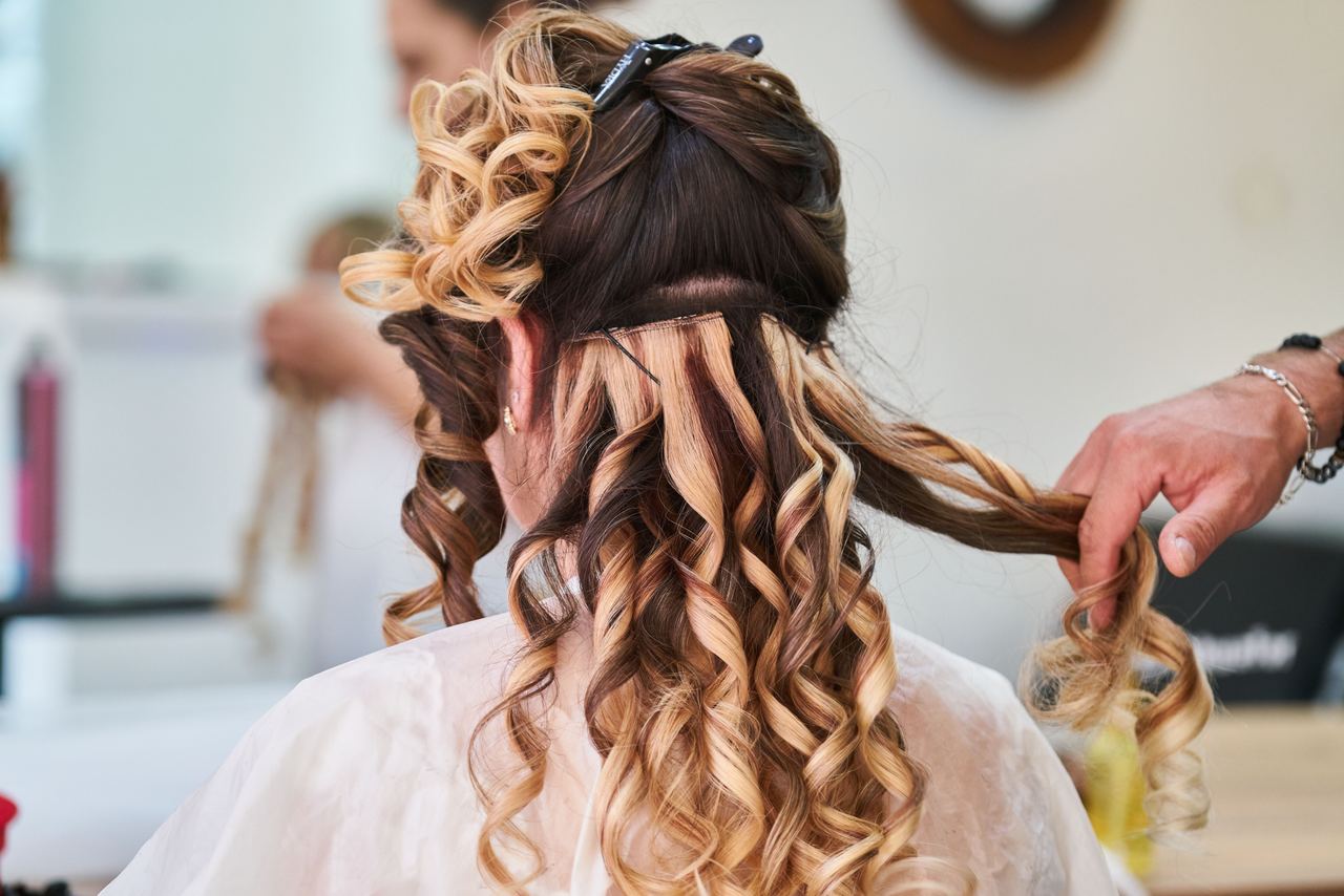 Stylist perfecting the curls on a woman's hair | Source: Pexels