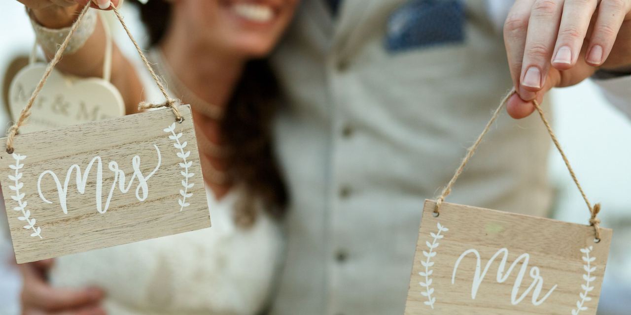 A close-up of newlyweds holding wooden boards with letterings 'Mrs' and 'Mr' | Source: Magnific