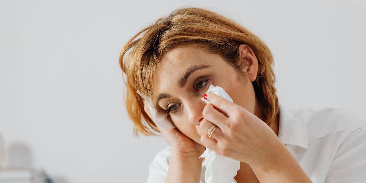A woman crying while wiping away her tears with a tissue | Source: Pexels