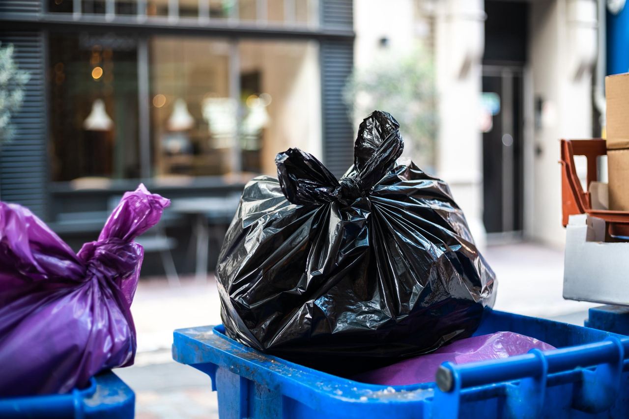 Purple and black bags of trash on a garbage bin | Source: Magnific