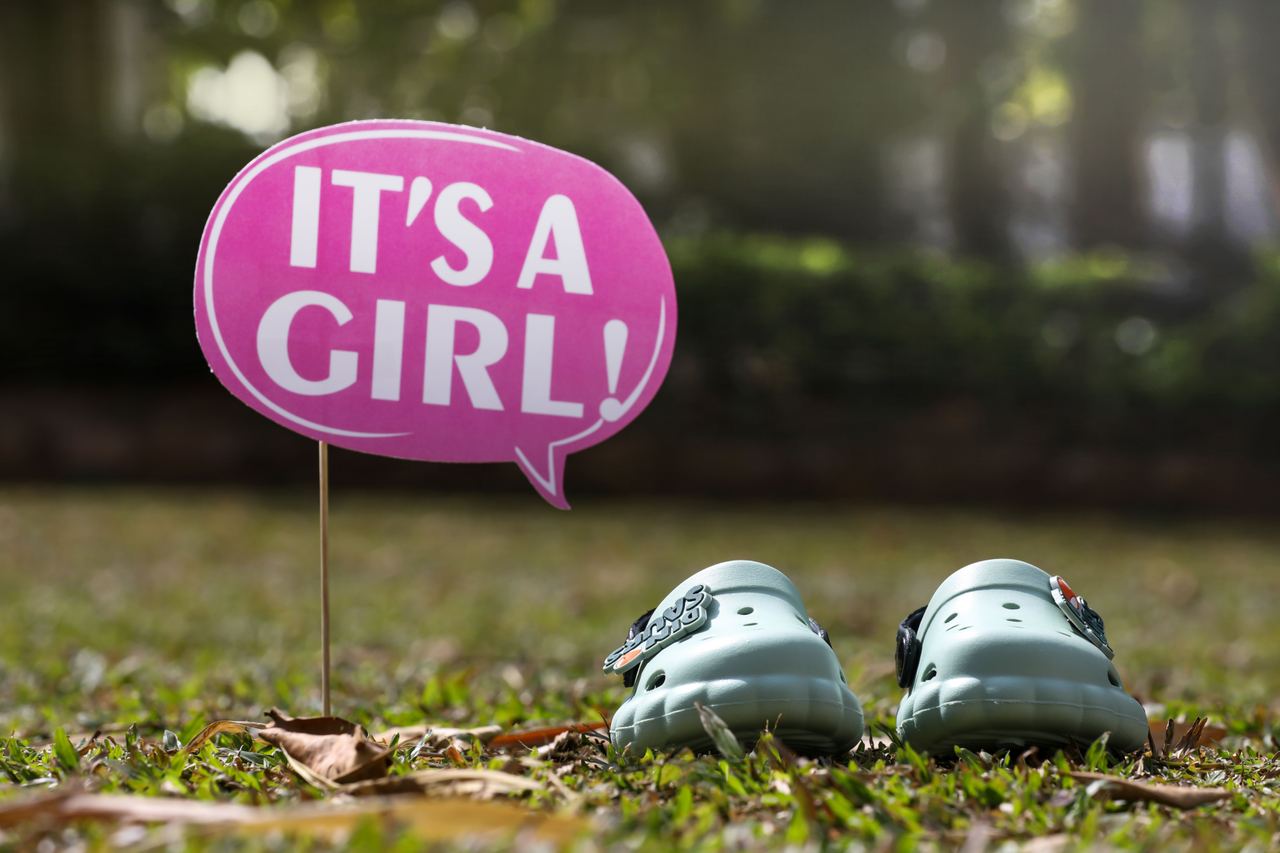 Pink “It’s a Girl!” sign next to baby shoes | Source: Pexels