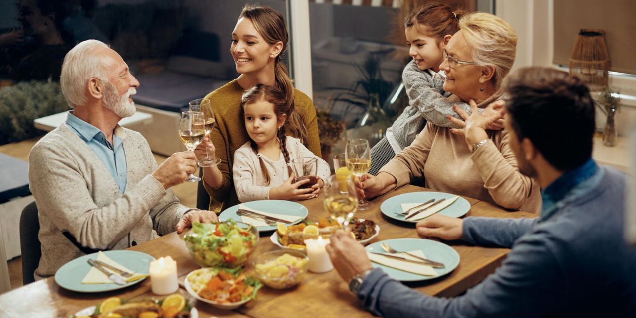 A family sharing a meal and raising glasses during a warm gathering around the dinner table | Source: Magnific