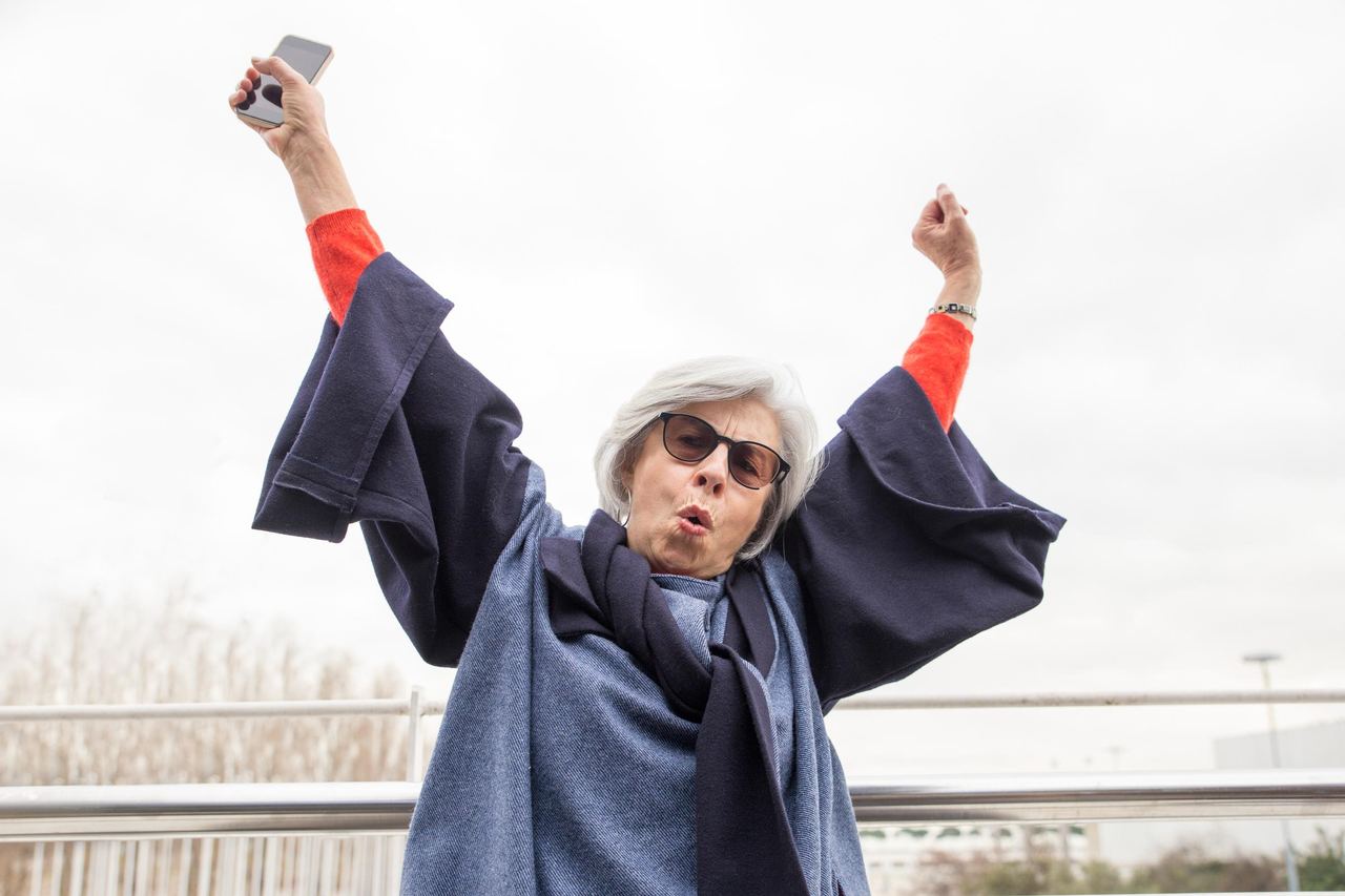Happy senior woman raising arms and screaming outdoors | Source: Magnific