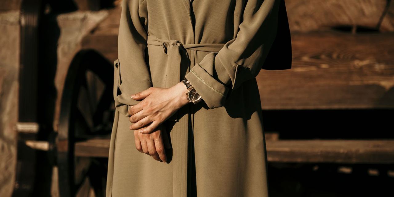 Person in a belted coat standing with hands clasped | Source: Pexels
