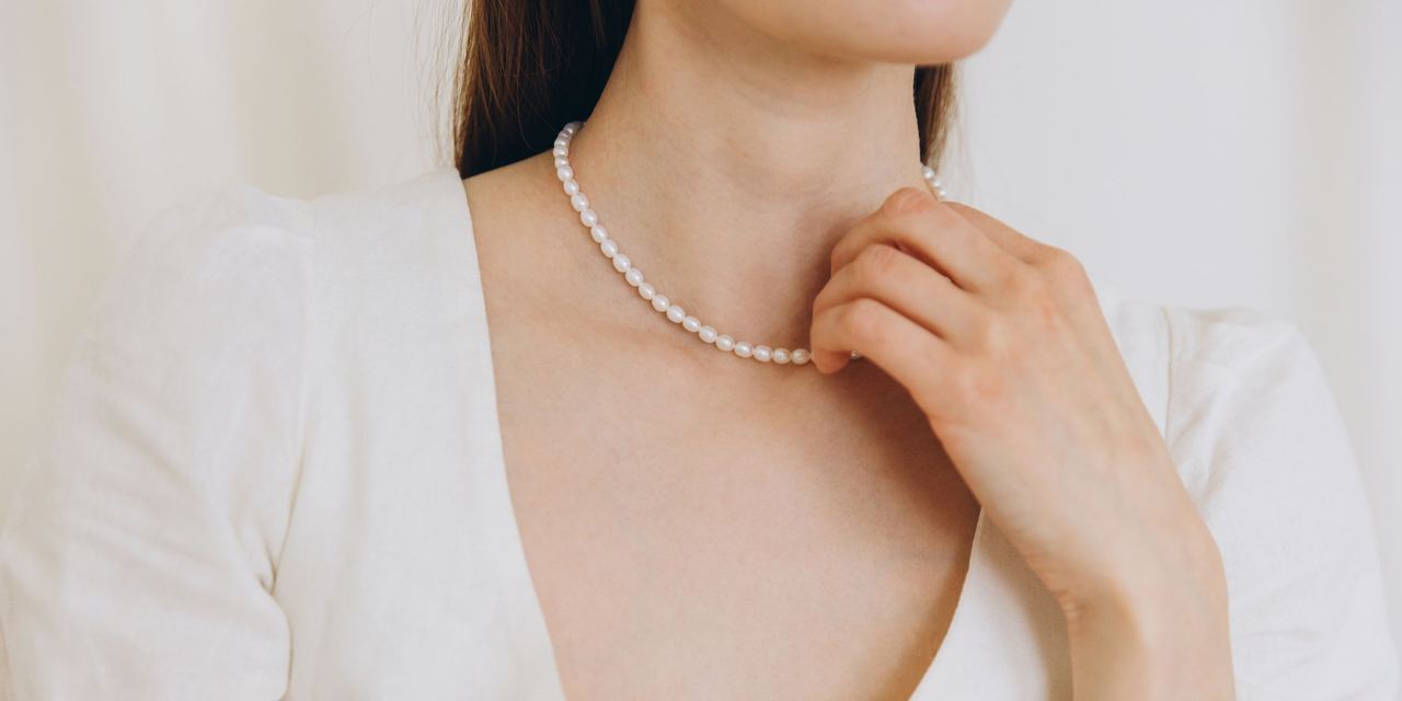 A woman touches a pearl necklace | Source: Shutterstock