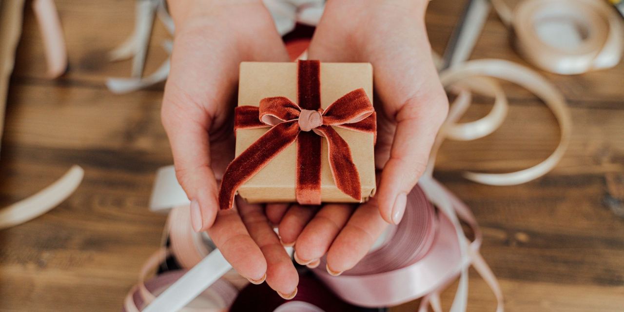 A woman's hands holding out a small gift-wrapped box | Source: Pexels