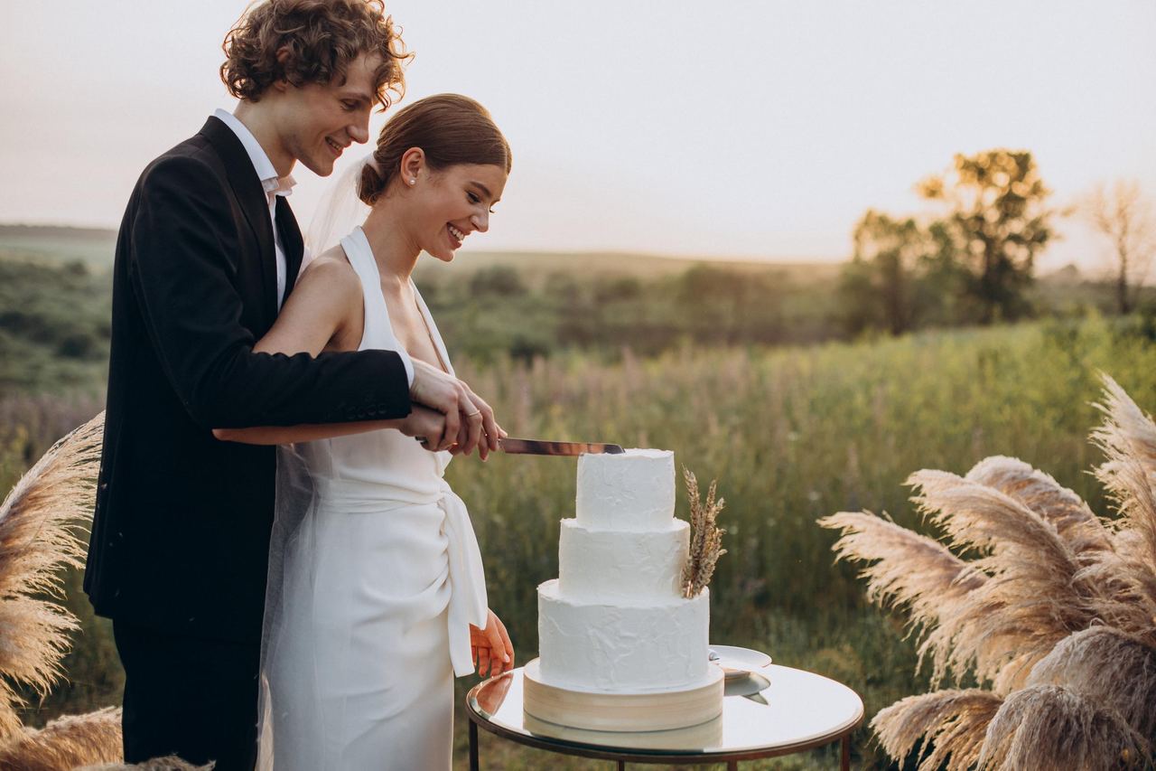 Young couple cutting their wedding cake | Source: Magnific