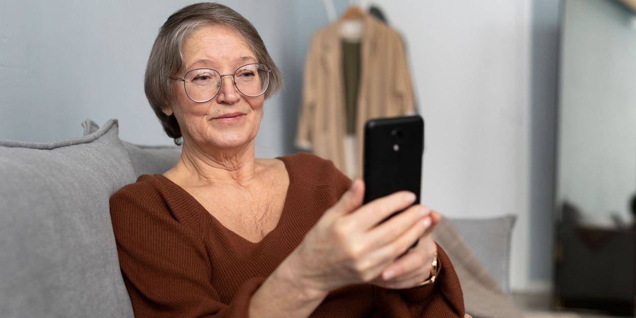An older woman using her phone | Source: Magnific