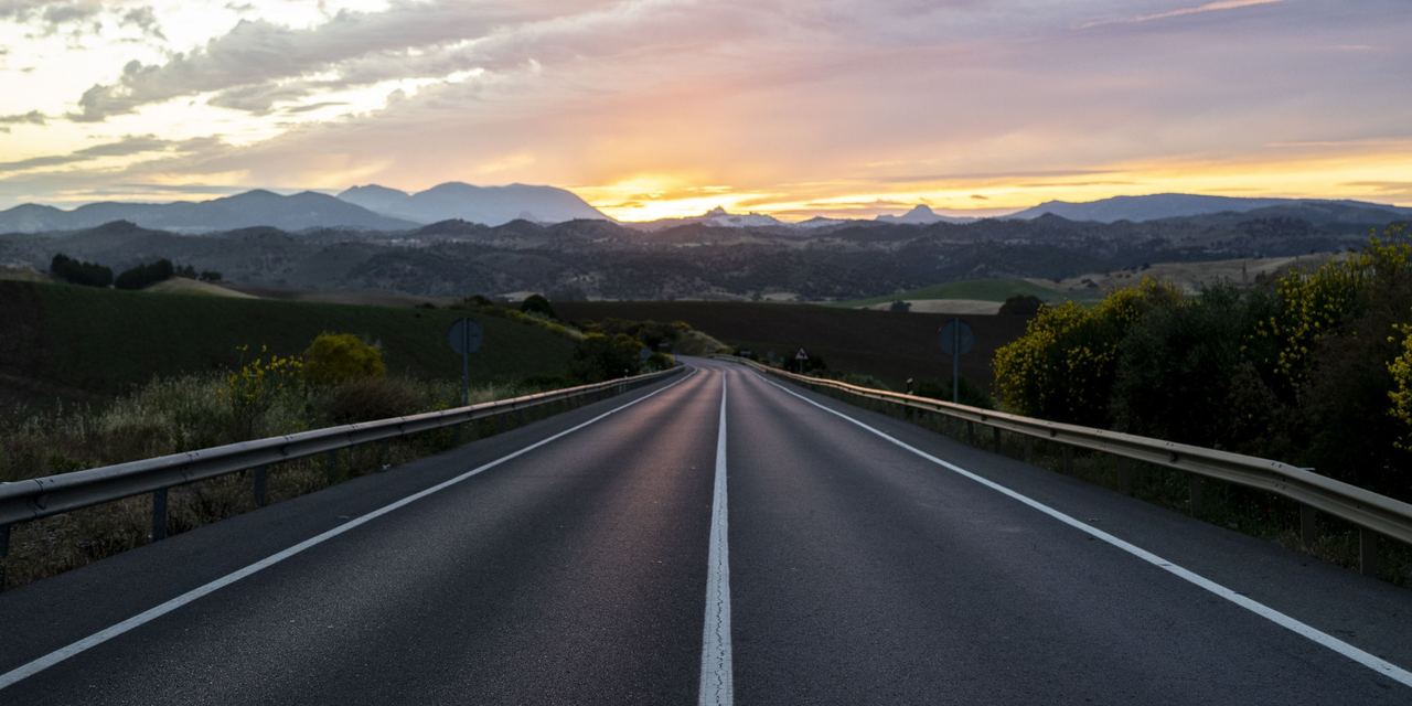 A view of an empty highway surrounded by hills under a cloudy sunset | Source: Magnific