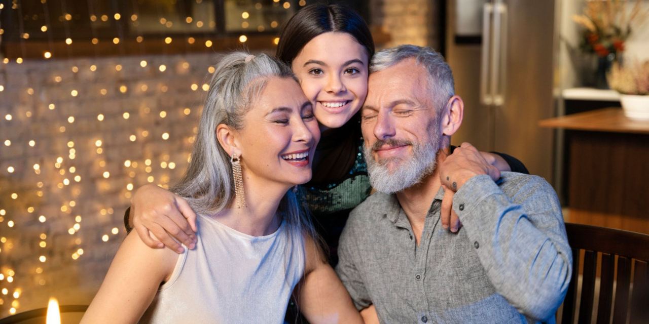 A smiling girl hugging her parents | Source: Freepik