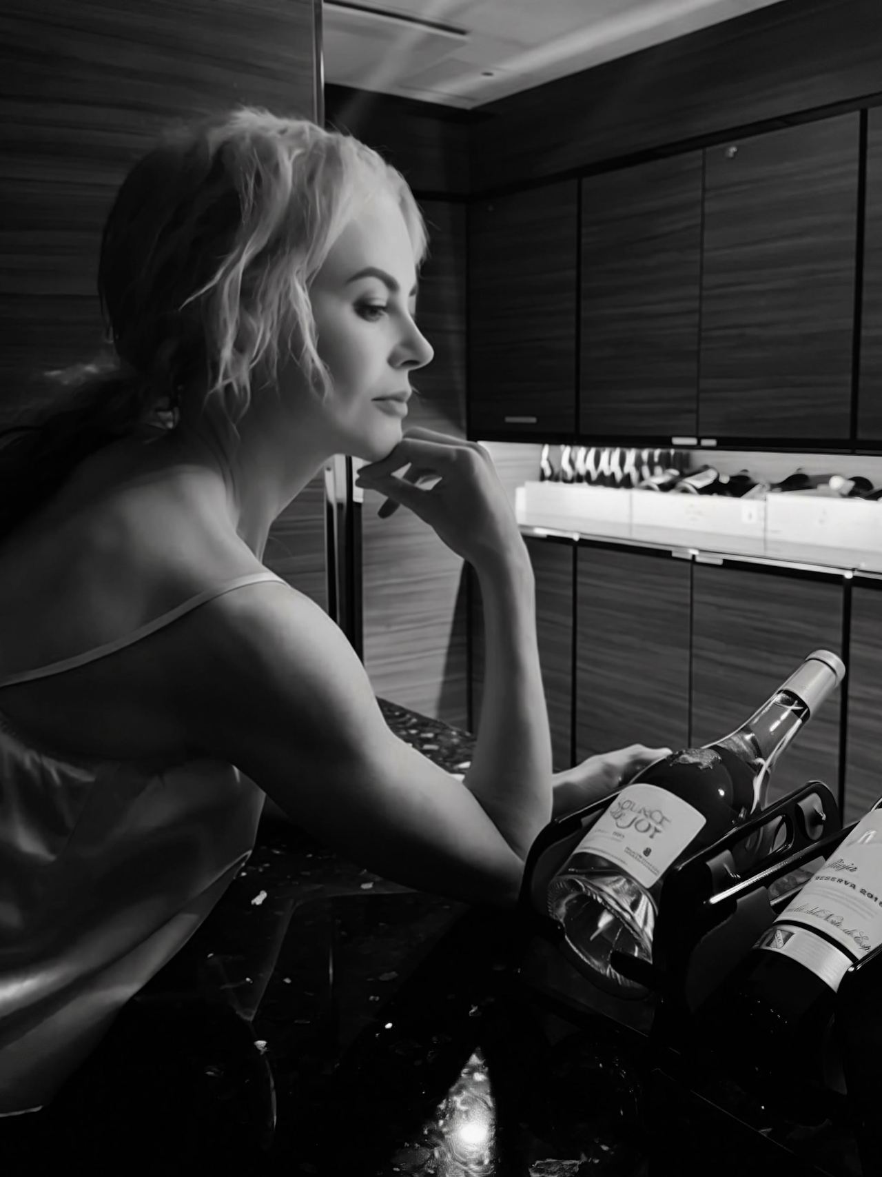 Kidman serves pure moody elegance in a atmospheric black-and-white portrait taken inside the ship's bar. Resting her chin on her hand in a delicate silk tank, she posed alongside fine wine bottles. | Source: Instagram/nicolekidman