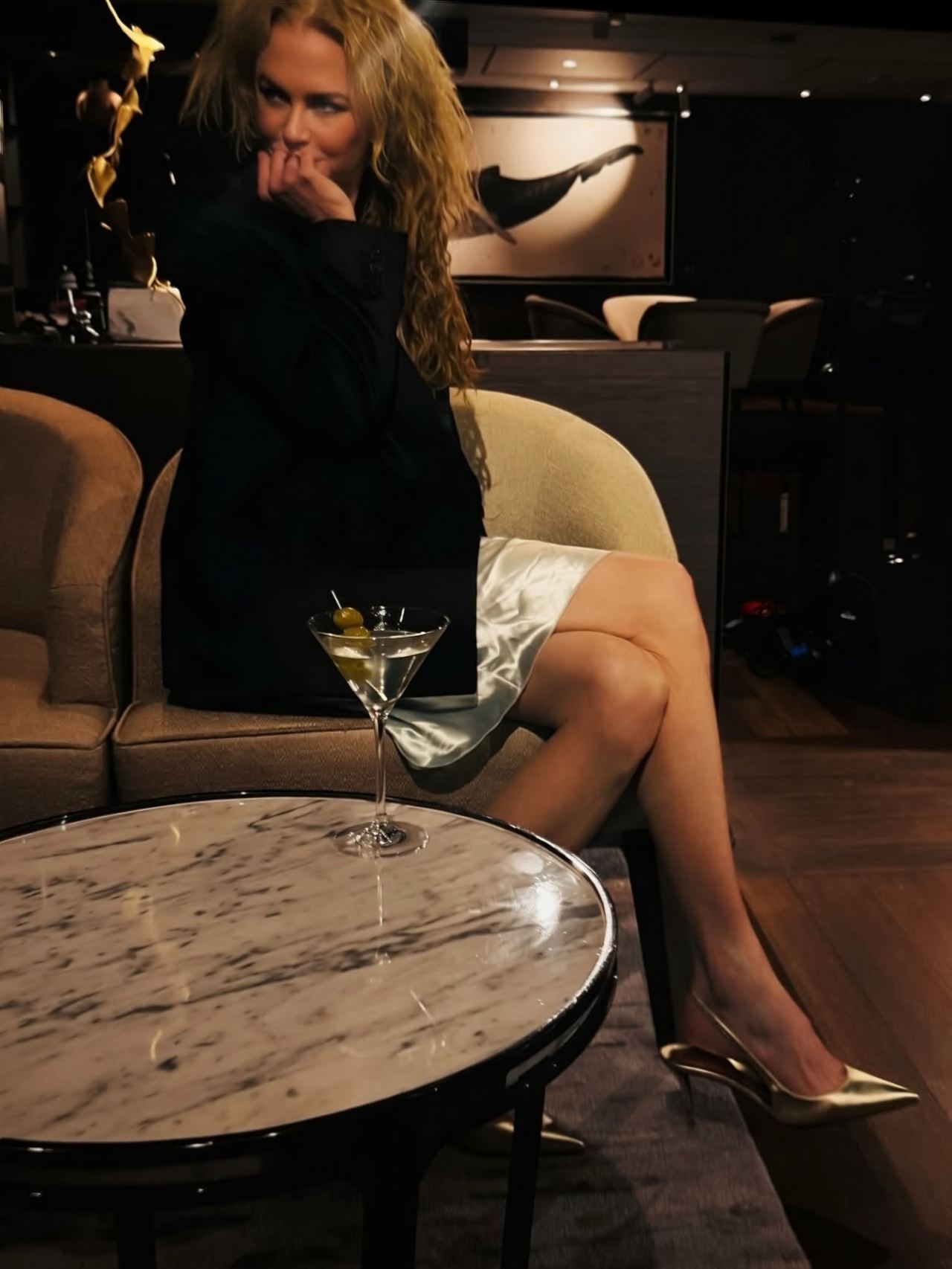 Glamming up for the evening, Nicole sips an olive-garnished martini in a satin slip dress and dark jacket. Metallic heels and soft natural waves completed her effortless night-out look. | Source: Instagram/nicolekidman