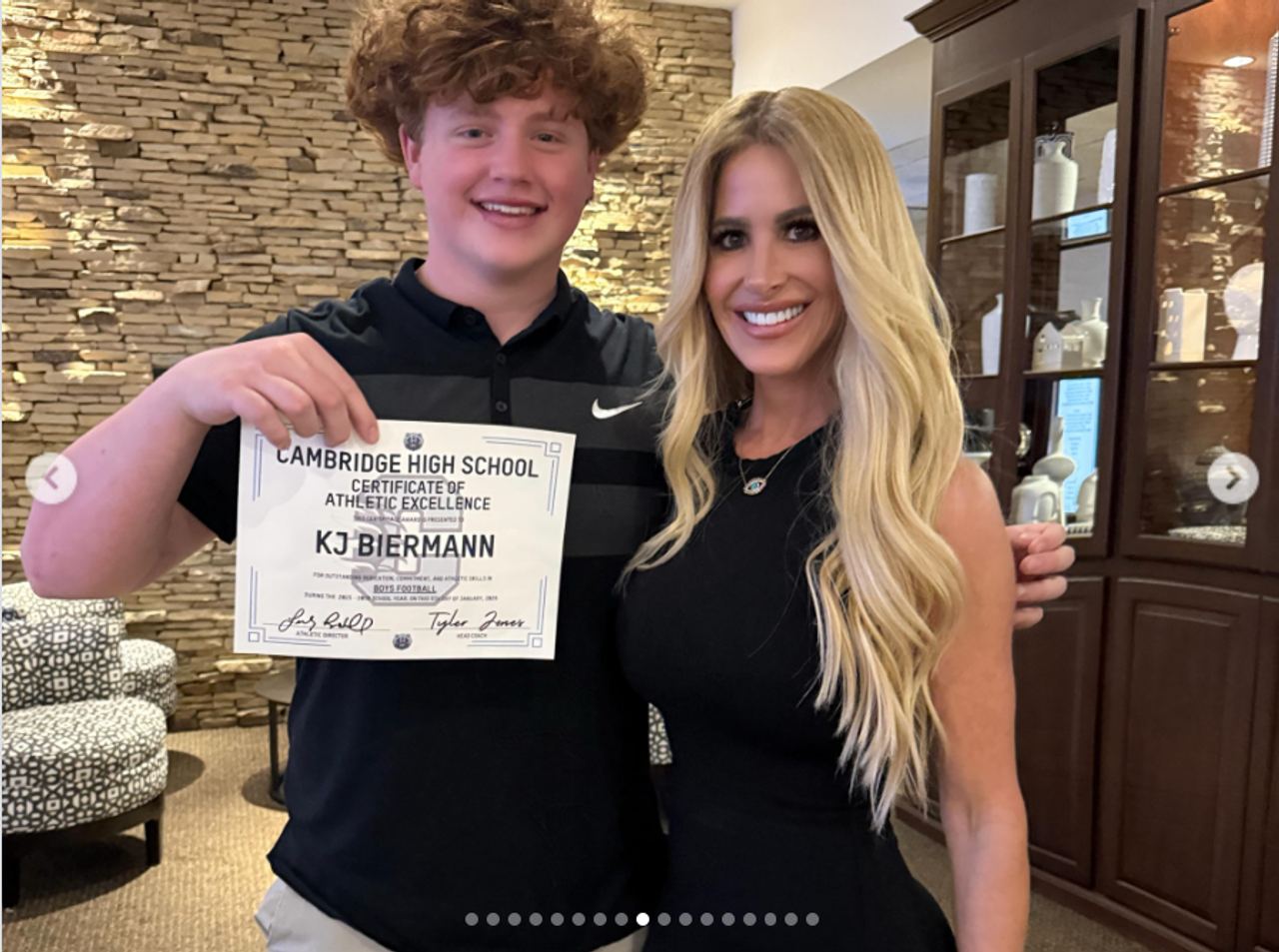 Kim Zolciak and her son KJ Biermann pose together as he holds a certificate of athletic excellence from Cambridge High School. The photo was shared by Kim weeks before news of his arrest, when she publicly celebrated her son as “her heart walking outside of her body” and praised his dedication to football. | Source: Instagram/kimzolciakbiermann