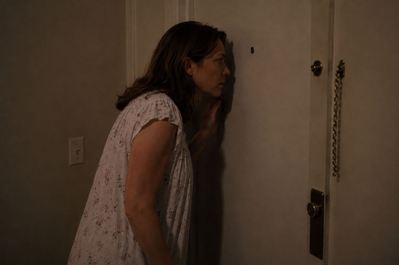 A woman looking through a peephole | Source: AmoMedia