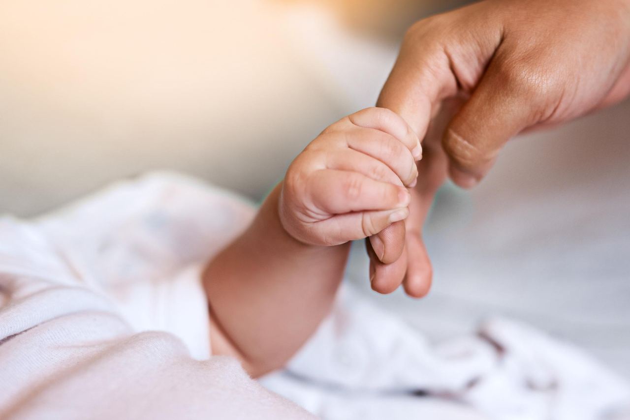 A baby holding a person's finger | Source: Shutterstock
