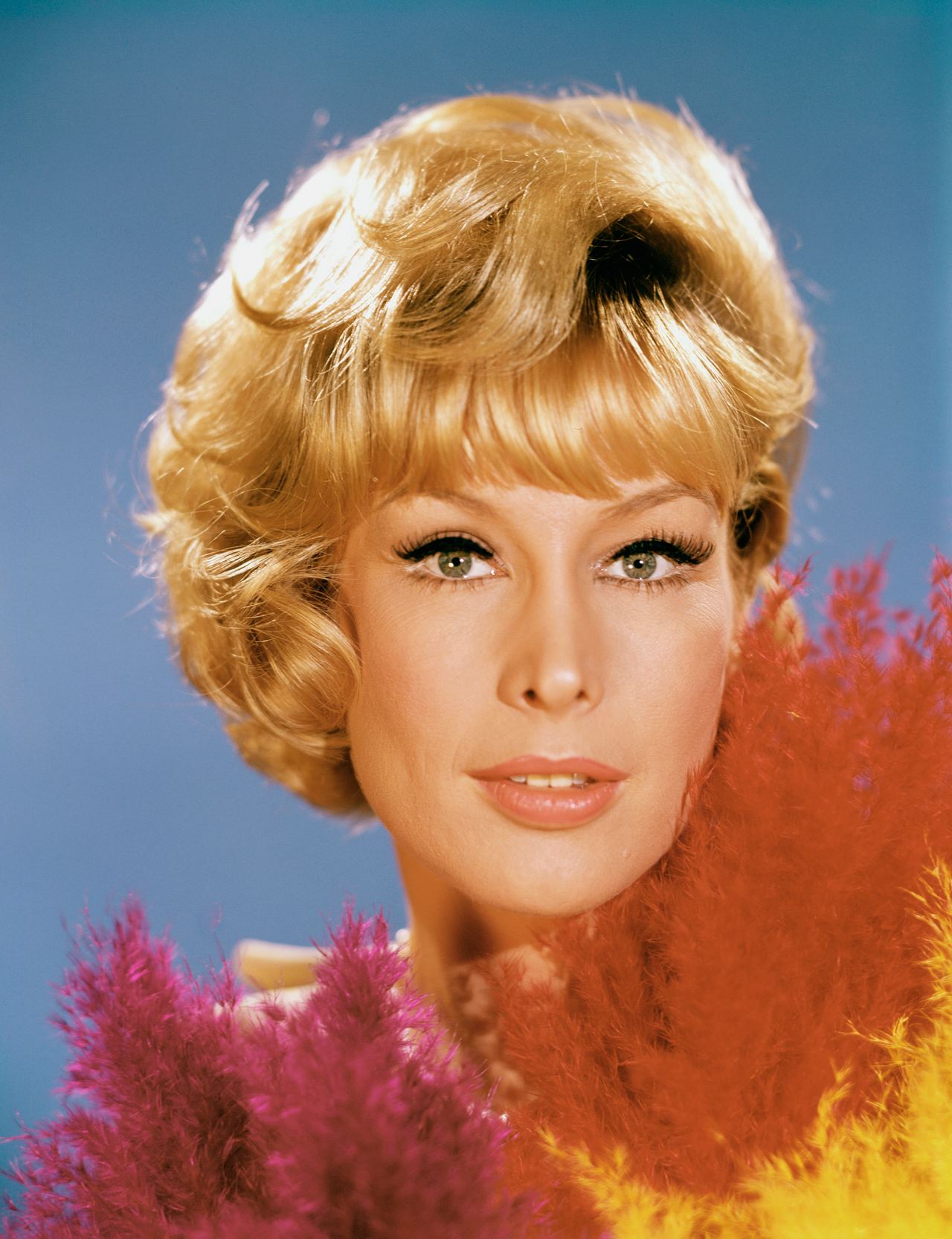 Barbara Eden appears as Jeannie with a polished blond bob, dramatic eye makeup, and colorful feathers framing her face in this "I Dream of Jeannie" Season one portrait. | Source: Getty Images