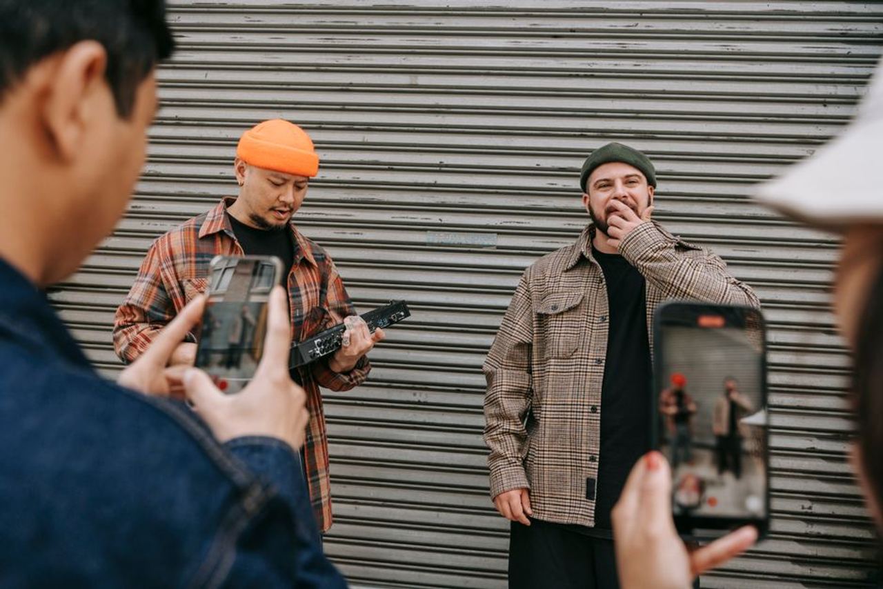 Street performance captured as people use smartphones to film musicians in urban setting.
