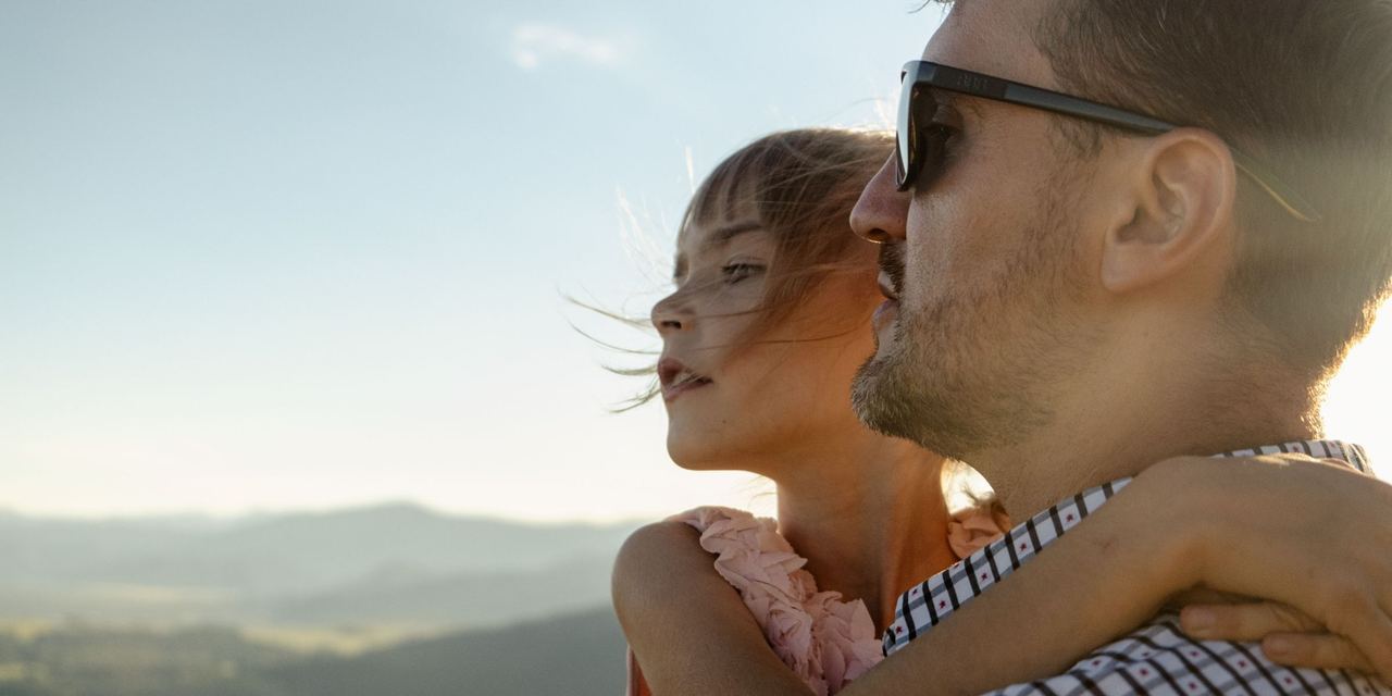 A close-up of a father carrying his daughter as they look into the horizon | Source: Pexels