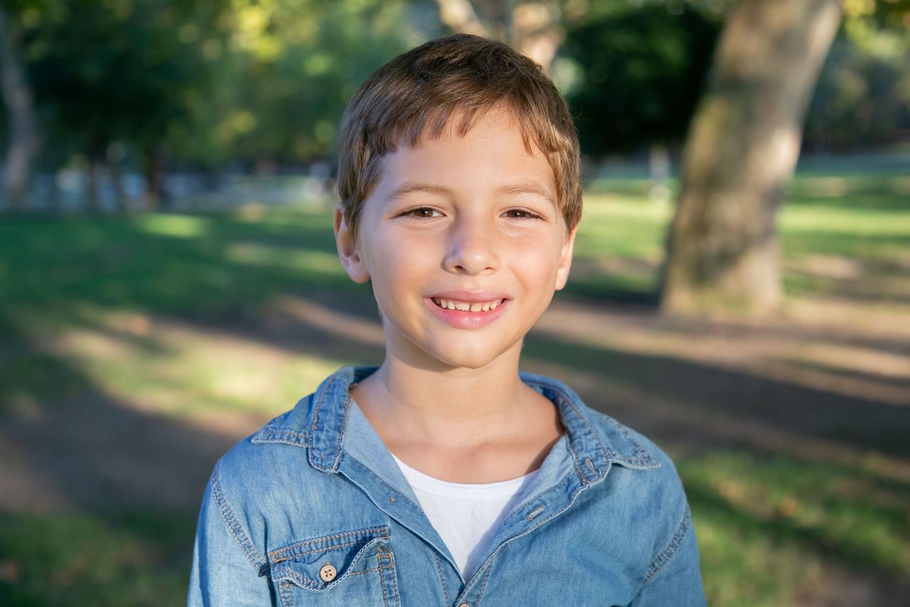 Portrait of a smiling boy outdoors in a sunny park | Source: Pexels
