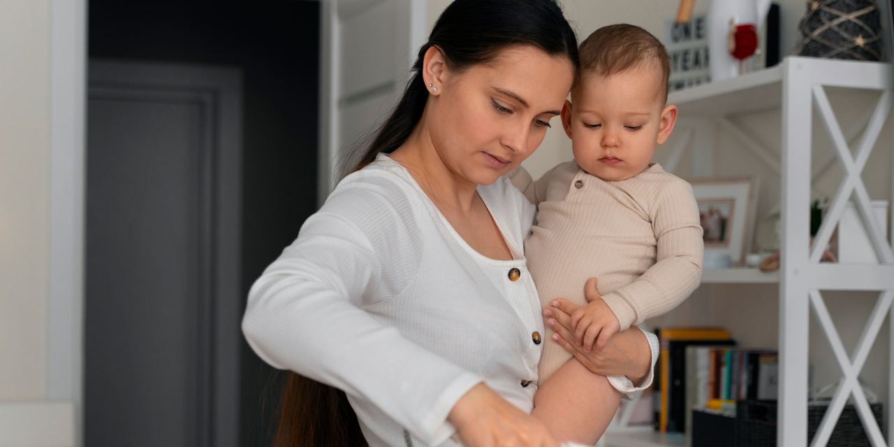 A mother cooking while holding her baby | Source: Magnific
