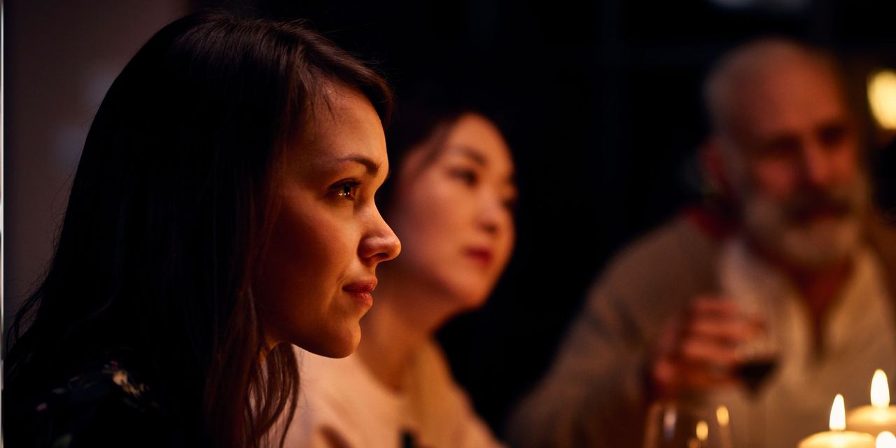 A serene-looking woman at a dinner party listening attentively | Source: Getty Images