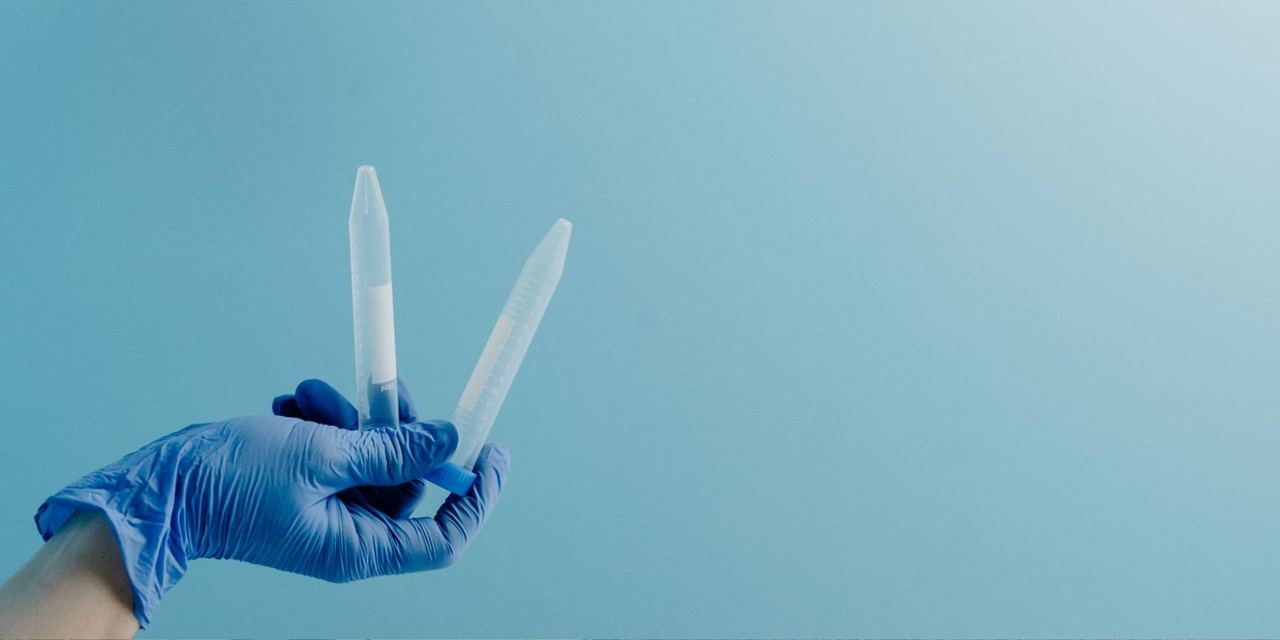 Gloved hand holding laboratory sample tubes | Source: Pexels