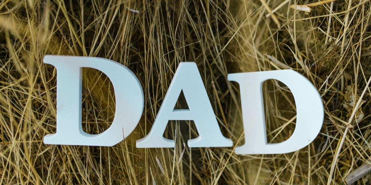 The word "DAD" spelled out with white wooden letters resting in dry grass | Source: Pexels