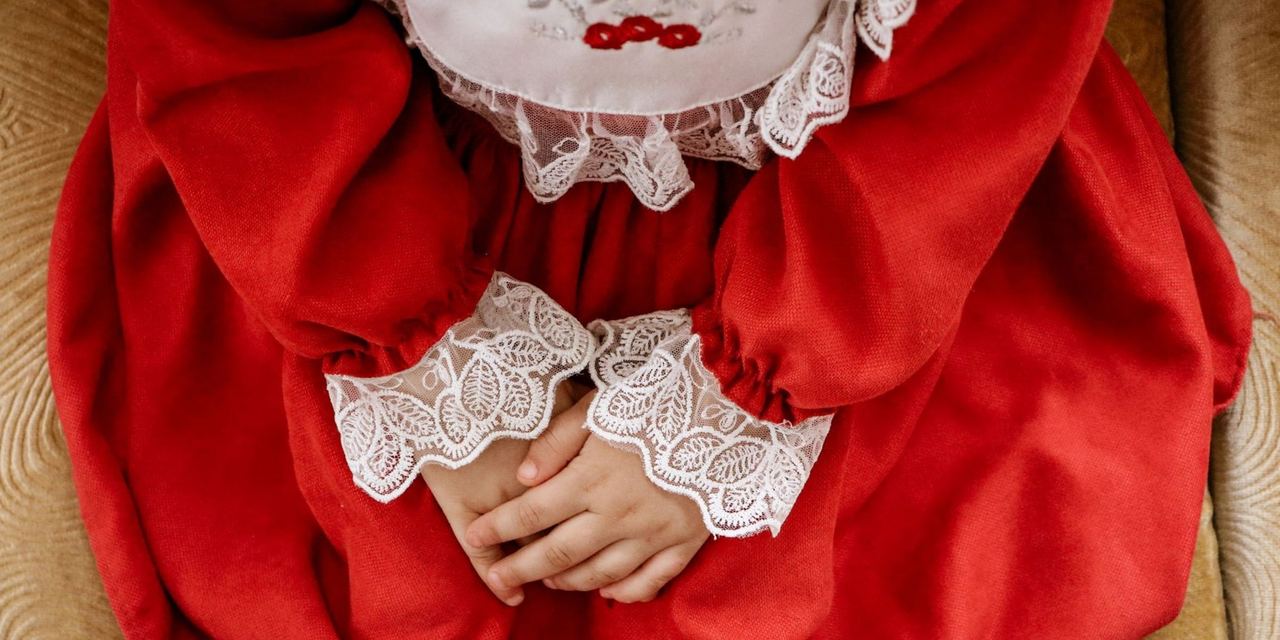 Child in an elegant red dress with white lace details | Source: Pexels