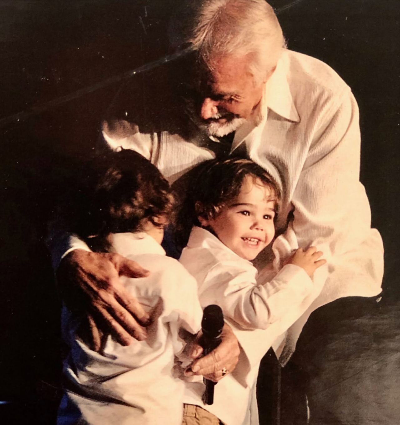 This tender throwback photo captures Kenny Rogers embracing his twin sons onstage, offering an early glimpse of the father-son bond behind the family resemblance debate that would follow the boys into adulthood. | Source: Facebook/Kenny Rogers