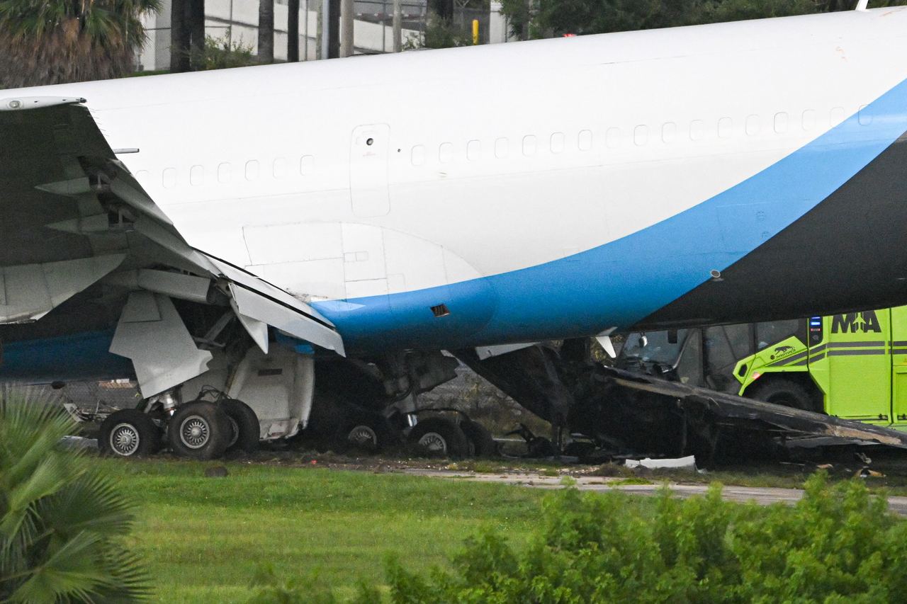 Damage is visible beneath the cargo aircraft after it traveled beyond the airport boundary. Firefighters encountered a complex engine compartment fire, while hazardous materials crews worked to mitigate a fuel leak. | Source: Getty Images