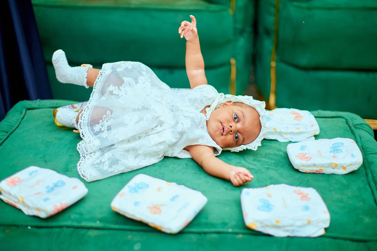 Cute baby in a white dress playing on a green sofa | Source: Pexels