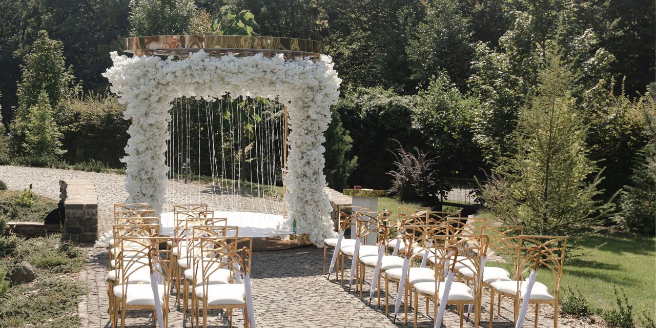 An elegant outdoor wedding ceremony setup surrounded by lush greenery | Source: Getty Images
