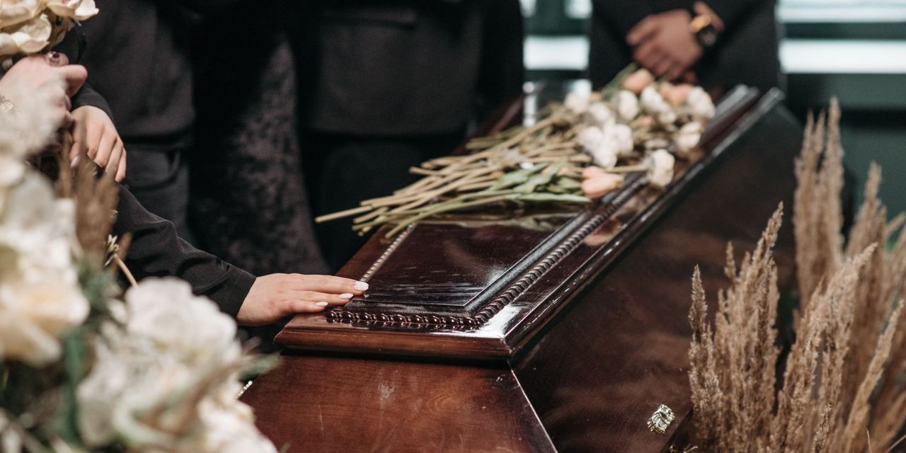 Close-up shot of people standing beside a coffin at a funeral | Source: Pexels